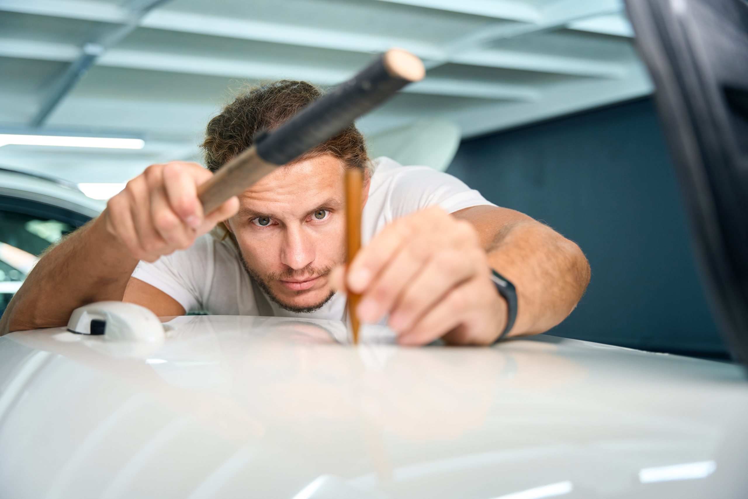 Specialist uses a straightening stick to level out body dents